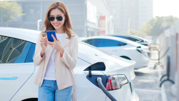 femme sur son cellulaire pendant que sa voiture charge